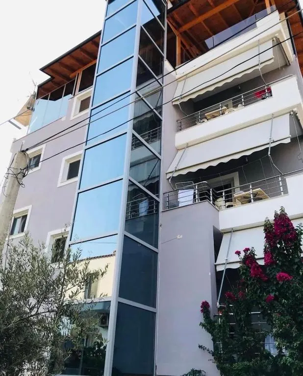 Dream Hotel exterior with private balconies, a glass-fronted elevator, shaded terraces, and Mediterranean greenery